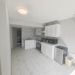 a kitchen with white cabinets and a white tile floor at Mountain Vista Inn & Suites - Parkway in Pigeon Forge