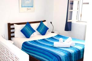 a bedroom with a bed with blue pillows and white shoes at Dar Latigeo in Essaouira