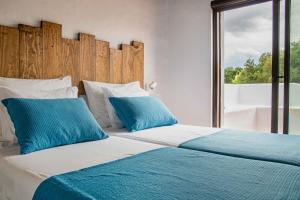 a bedroom with two beds with blue pillows and a window at Casa da Bolota T1 - Monte do Serrado de Baixo in Évora