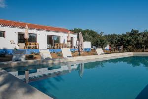 a pool with chairs and umbrellas next to a house at Casa da Azeitona T1 - Monte do Serrado de Baixo in Évora