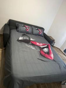 a black bed with black and red pillows on it at Charmante studio ligne 13 tram 5 saint denis in Pierrefitte-sur-Seine