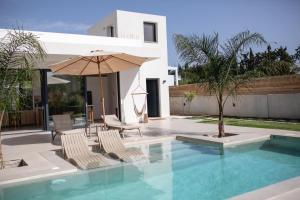 a swimming pool with two chairs and an umbrella at Villa Kala Loutraki - Private Pool & Sauna I Beach in Loutraki