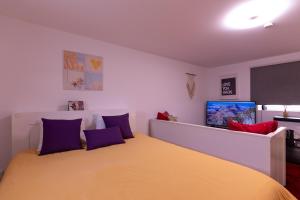 a bedroom with a large yellow bed with purple pillows at Perafita Yellow House - EcoHost in Perafita
