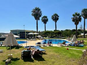 a group of people laying in lawn chairs by a pool at Apartamentos Santa Teresinha in Alvor