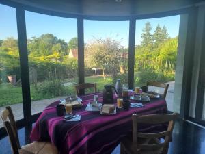 a table with a purple table cloth on it with a window at Villa NICAISE in Moisenay