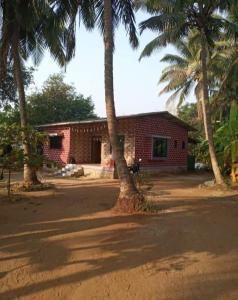 a brick house with palm trees in front of it at Coconut Village Resort in Alībāg +52 photos