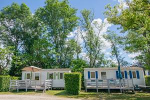 a caravan with a porch and chairs and trees at Camping Onlycamp La Colombière in Pesmes