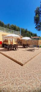 un groupe de tables de pique-nique et de parasols sur une plage dans l'établissement Casa Pejão Do Paraíso, à Castelo de Paiva 13 autres photos