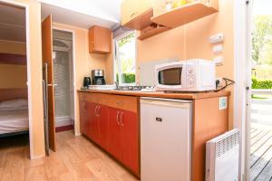 a small kitchen with a microwave and a refrigerator at Camping Onlycamp La Colombière in Pesmes