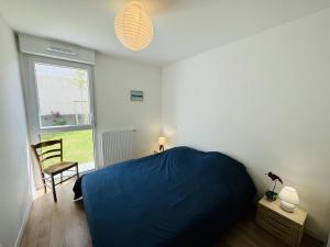 une chambre avec un lit bleu et une chaise dans l'établissement 3 pièces 68m², jardin clos, 150m plage, wifi, à Saint-Pierre-Quiberon