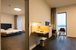 a hotel room with a bed and a desk with a phone at Domein Polderwind in Zuienkerke