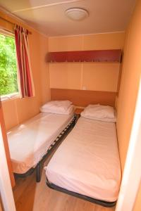 two beds in a small room with a window at Camping Onlycamp La Colombière in Pesmes