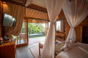 a bedroom with a bed with curtains and a television at The Patra Villa Sebatu by Dhananjaya Hospitality in Tampaksiring +64 photos