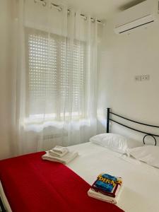 a white bed with a red blanket and a window at Casa ORI in Montesilvano