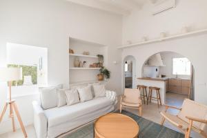 a living room with a white couch and a kitchen at BiniVento- Lovely villa with pool near the beach in Binibeca