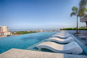 een zwembad met ligstoelen aan de zijkant van een gebouw bij 1BR 2BA | Romantic Zone w/ Rooftop Pool & Gym in Puerto Vallarta