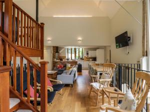 a living room with a staircase and a kitchen at Quill Farm Barn in Campsea Ashe