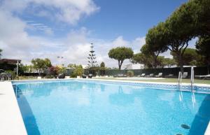 a large blue swimming pool with trees in the background at Hotel Albaida Nature in Mazagón