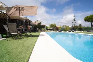 a pool with a table and chairs and an umbrella at Hotel Albaida Nature in Mazagón
