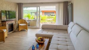 a living room with a white couch and a fireplace at Ferienwohnung Apartment Seeterrasse - im Maarberg Resort - in Schalkenmehren am See in Schalkenmehren