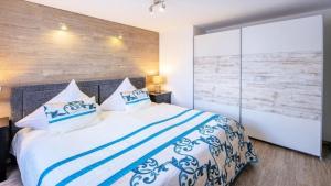 a bedroom with a bed with blue and white pillows at Ferienwohnung Apartment Seeterrasse - im Maarberg Resort - in Schalkenmehren am See in Schalkenmehren
