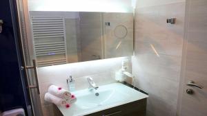 a bathroom with a sink and a mirror at Ferienwohnung Apartment Seeterrasse - im Maarberg Resort - in Schalkenmehren am See in Schalkenmehren +6 photos