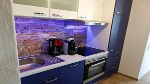 a kitchen with blue cabinets and a sink and a brick wall at Ferienwohnung Studio Vulkanhöhe - im Maarberg Resort - in Schalkenmehren am See in Schalkenmehren