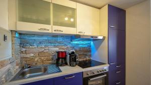 a kitchen with a sink and a stone wall at Ferienwohnung Studio Vulkanhöhe - im Maarberg Resort - in Schalkenmehren am See in Schalkenmehren