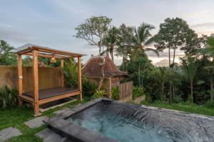 a swimming pool with a gazebo next to a house at The Patra Villa Sebatu in Tampaksiring