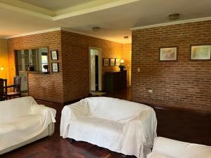 a living room with two white couches and a brick wall at La Arboleda in Corrientes