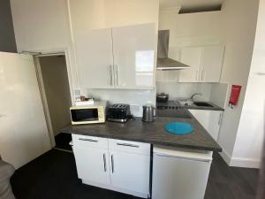 a small kitchen with white cabinets and a microwave at Farina No2, Sea view apartment sleeping 4 guests in Bridlington