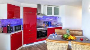 a kitchen with red cabinets and a table with a bowl of fruit at Ferienwohnung Maarpanorama in Schalkenmehren am See in Schalkenmehren
