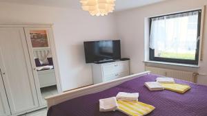 a bedroom with a purple bed and a tv at Ferienwohnung Seeblick II in Schalkenmehren
