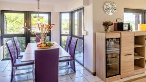 a kitchen and dining room with a table and purple chairs at Ferienwohnung Seeblick II in Schalkenmehren