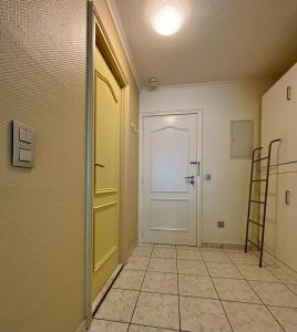 a hallway with a white door and a tiled floor at Studio Sia - Lichtrijke studio met balkon met zijzeezicht in hartje de Panne in De Panne