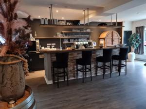 a kitchen with a bar with black bar stools at B&B Hartje Exloo in Exloo