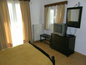 a bedroom with a bed and a television on a dresser at Hotel Filioppi in Agios Kirykos
