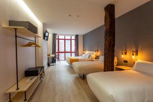 a hotel room with two beds and a tree at Casual Fuentes in Bilbao