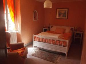 a bedroom with a bed with orange walls and a window at Maison charmante à Les Junies avec vue sur jardin in Les Junies