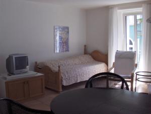 Schlafzimmer mit einem Bett, einem TV und einem Tisch in der Unterkunft Appartamenti della Ruga in Ascona