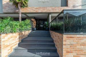 a staircase leading to a building with a palm tree at DRL - Apartamentos a 300m da Praia de Bombinhas in Bombinhas