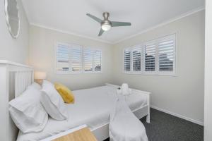 a white bedroom with a bed and a ceiling fan at City Love Affair On Stanley in Townsville