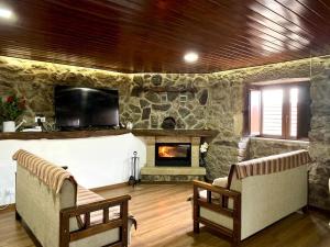 a living room with two chairs and a stone fireplace at Casa Torre do Sino in Montalegre