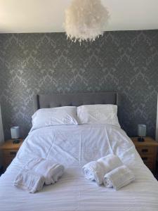 a white bed with two towels on top of it at Manor Close in Wrafton +5 photos