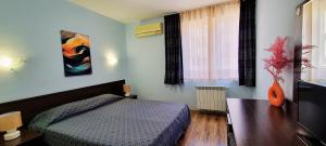 a bedroom with a bed and a table and a window at Hotel Bijou in Burgas