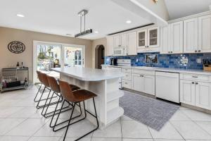 a kitchen with white cabinets and a large island with bar stools at Hamptons Waterfront - Shinnecock Bay in Hampton Bays +4 photos