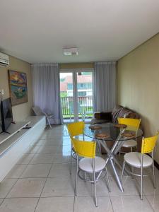 ein Wohnzimmer mit einem Glastisch und gelben Stühlen in der Unterkunft Club Meridional Carneiros in Tamandaré