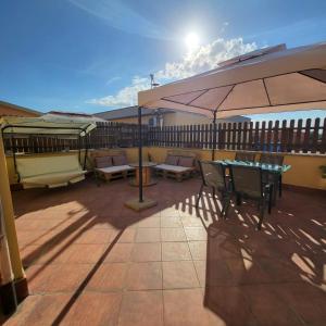 eine Terrasse mit Sonnenschirm und Tisch und Stühlen in der Unterkunft La terrazza in Tarquinia