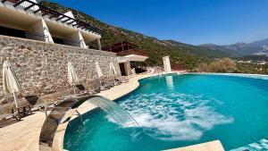 a swimming pool with a waterfall in front of a building at Kaleli Deluxe Homes in Kas