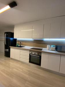 a kitchen with white cabinets and a black refrigerator at Villa con piscina privada in Alicante